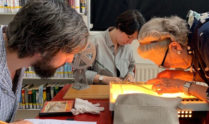 Drei Menschen arbeitend vor einem Bücherregal