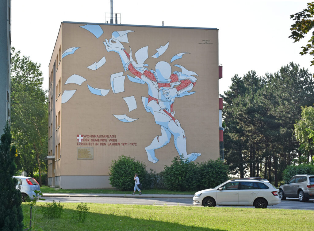 Riesiges Graffiti auf Gemeindebau von einer Figur die sich in Zettel auflöst