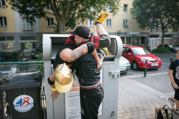 Eine Person wirft eine andere in die Altkleidersammelbox