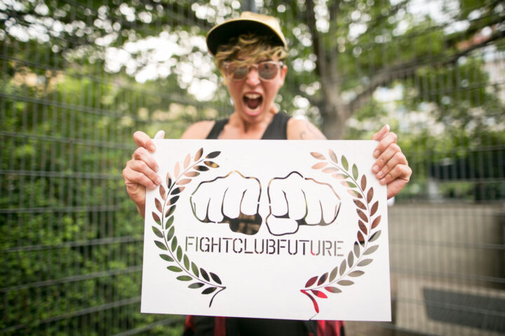 Person schreit und hält ein Schild auf dem zwei Fäuste sind mit der Aufschrift "Fightclubfuture"