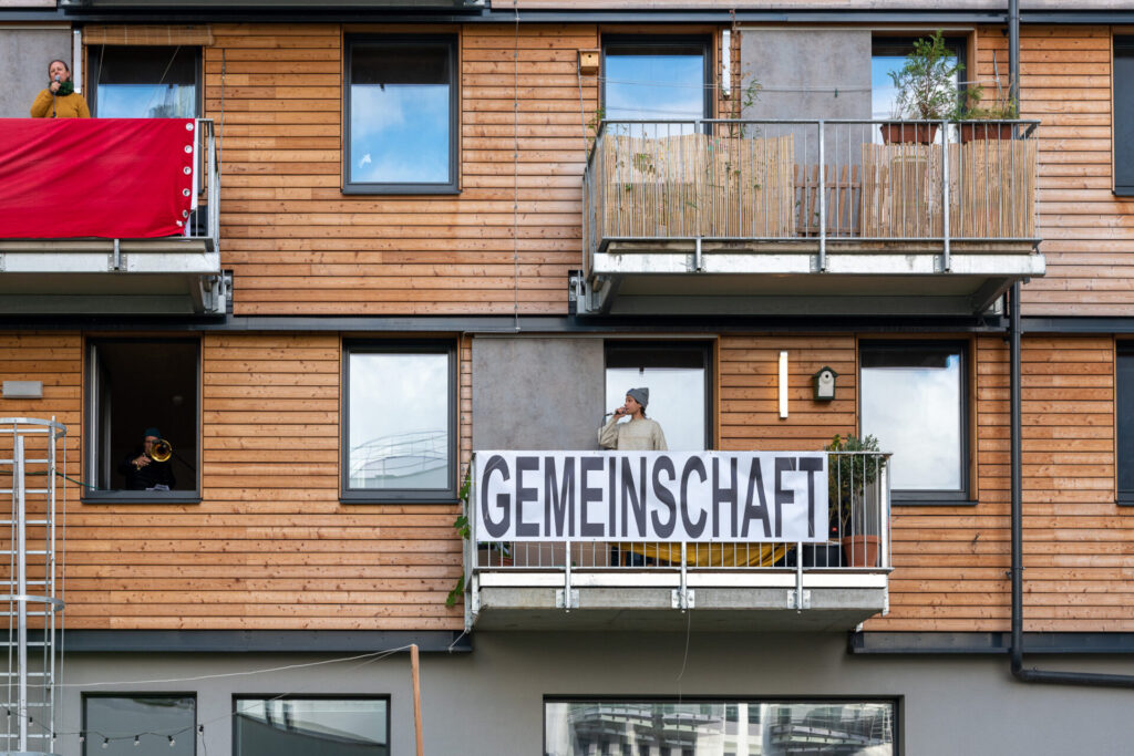 Balkone mit Performer:innen und Schild mit Aufschrift 