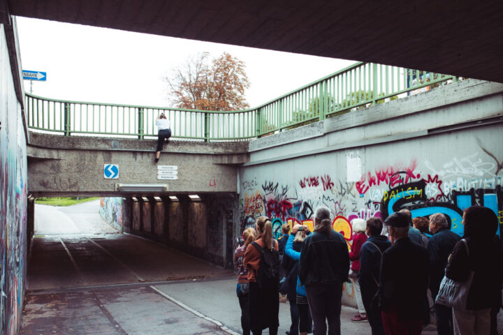 Frau klettert über Sicheheitsgitter über Unterführung herunter