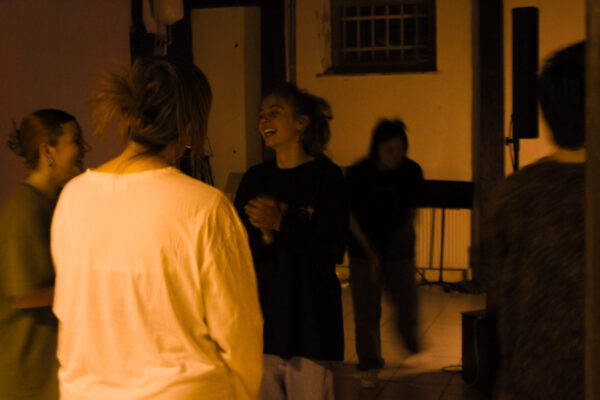 Eine weiblich gelesene Person lacht und redet mich zwei weiteren Personen bei einem Workshop