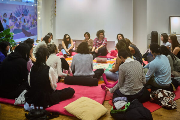 Group of people sitting down on a pink rug